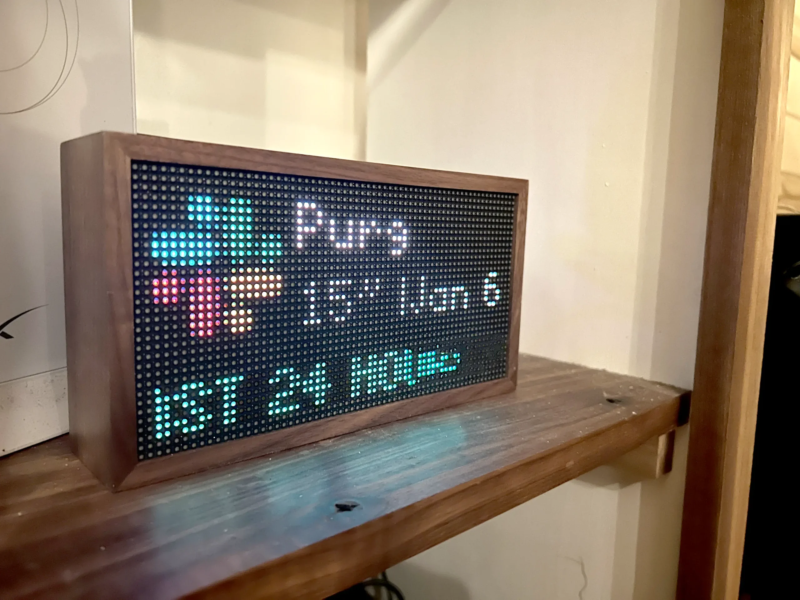 a walnut Tidbyt showing the Purgatory weather report